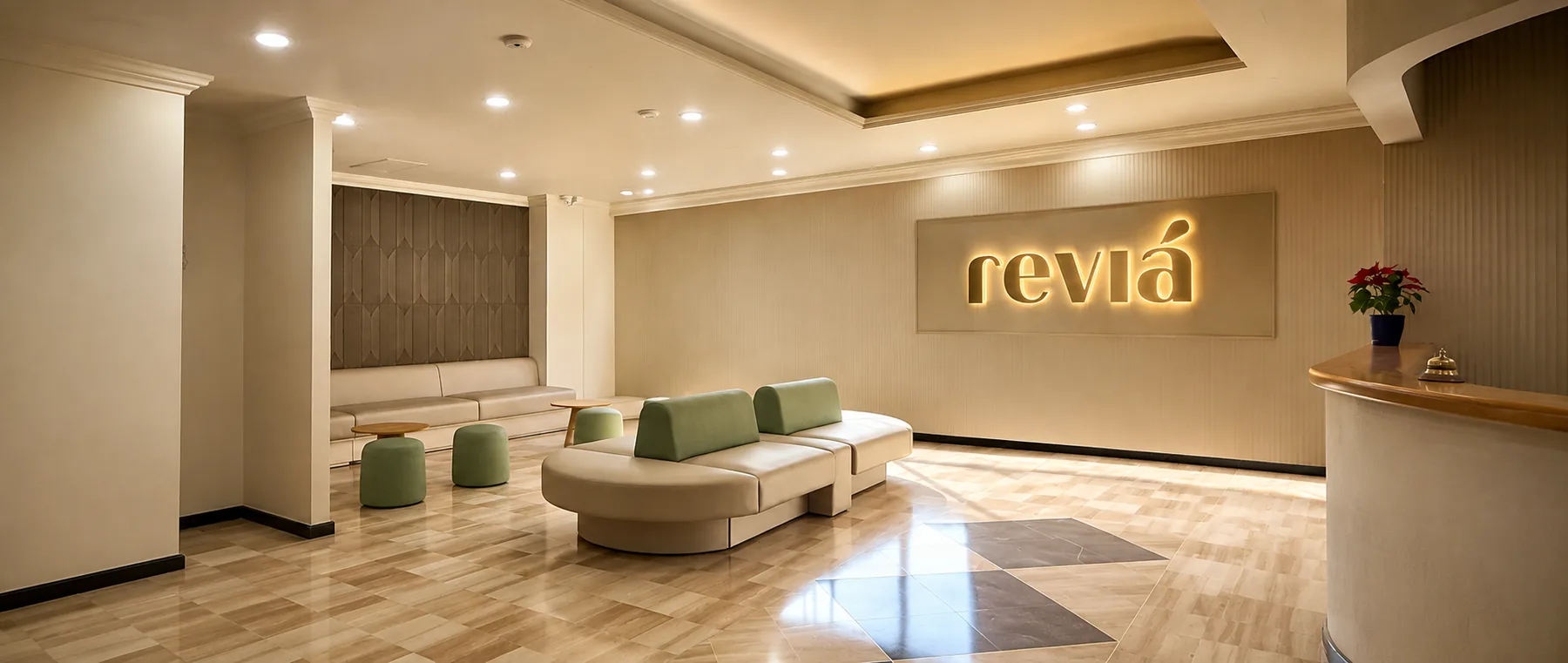 Recepción de la sede de Reviá en Bogotá: mostrador de madera clara, el logotipo iluminado en la pared y la sala de espera al fondo.